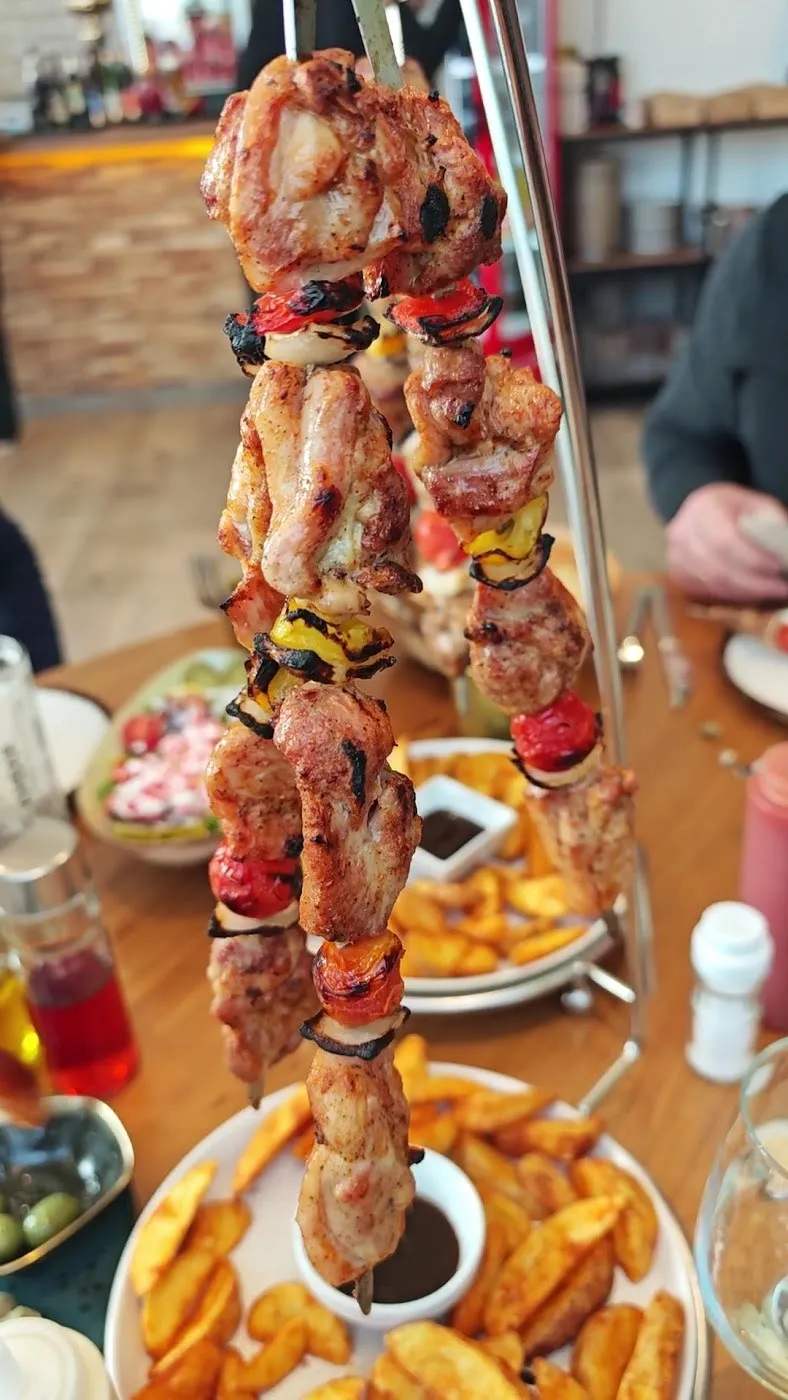 Brochetas de pollo colgadas sobre patatas gajo