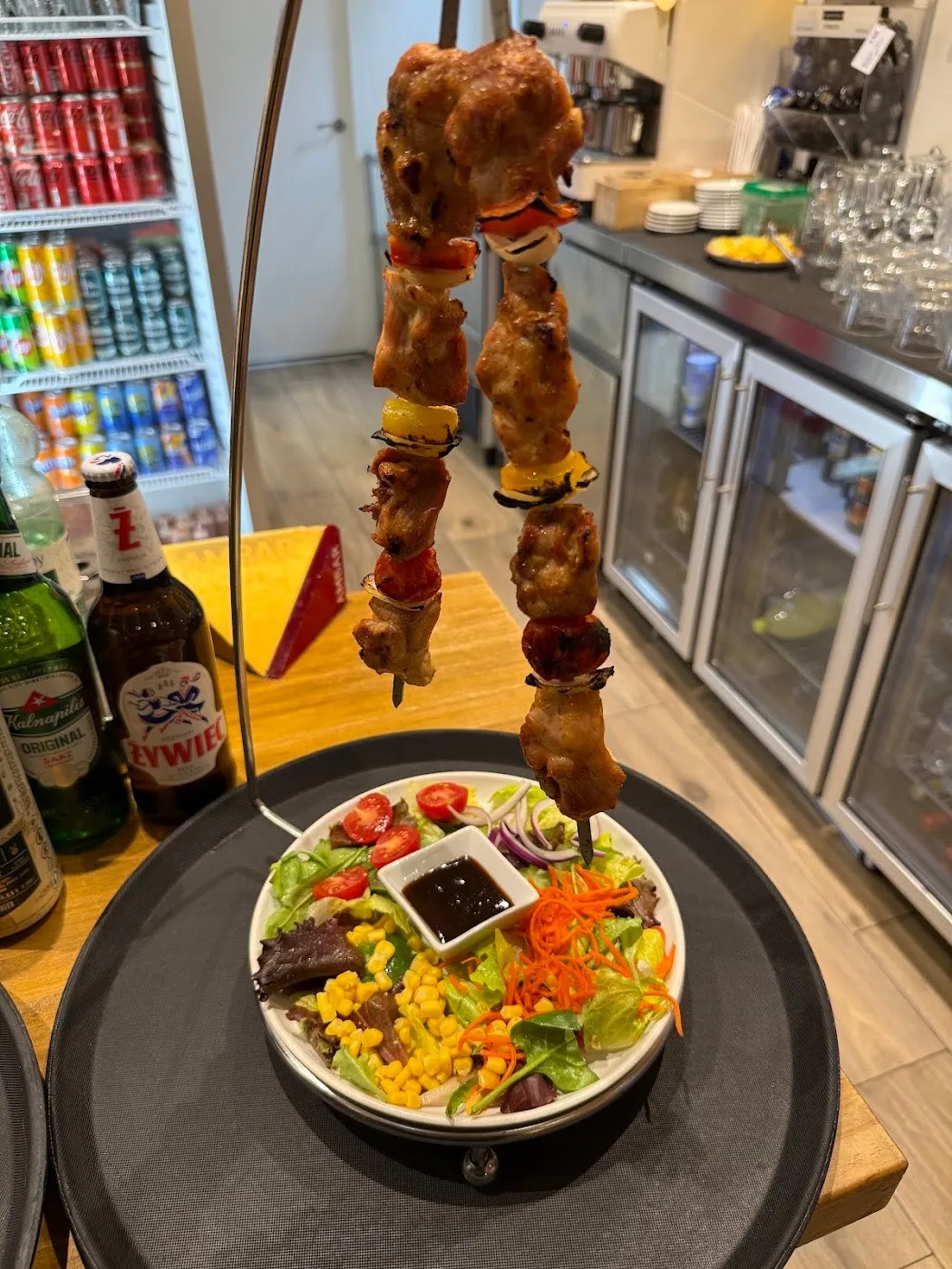 Brochetas de pollo colgadas sobre una ensalada