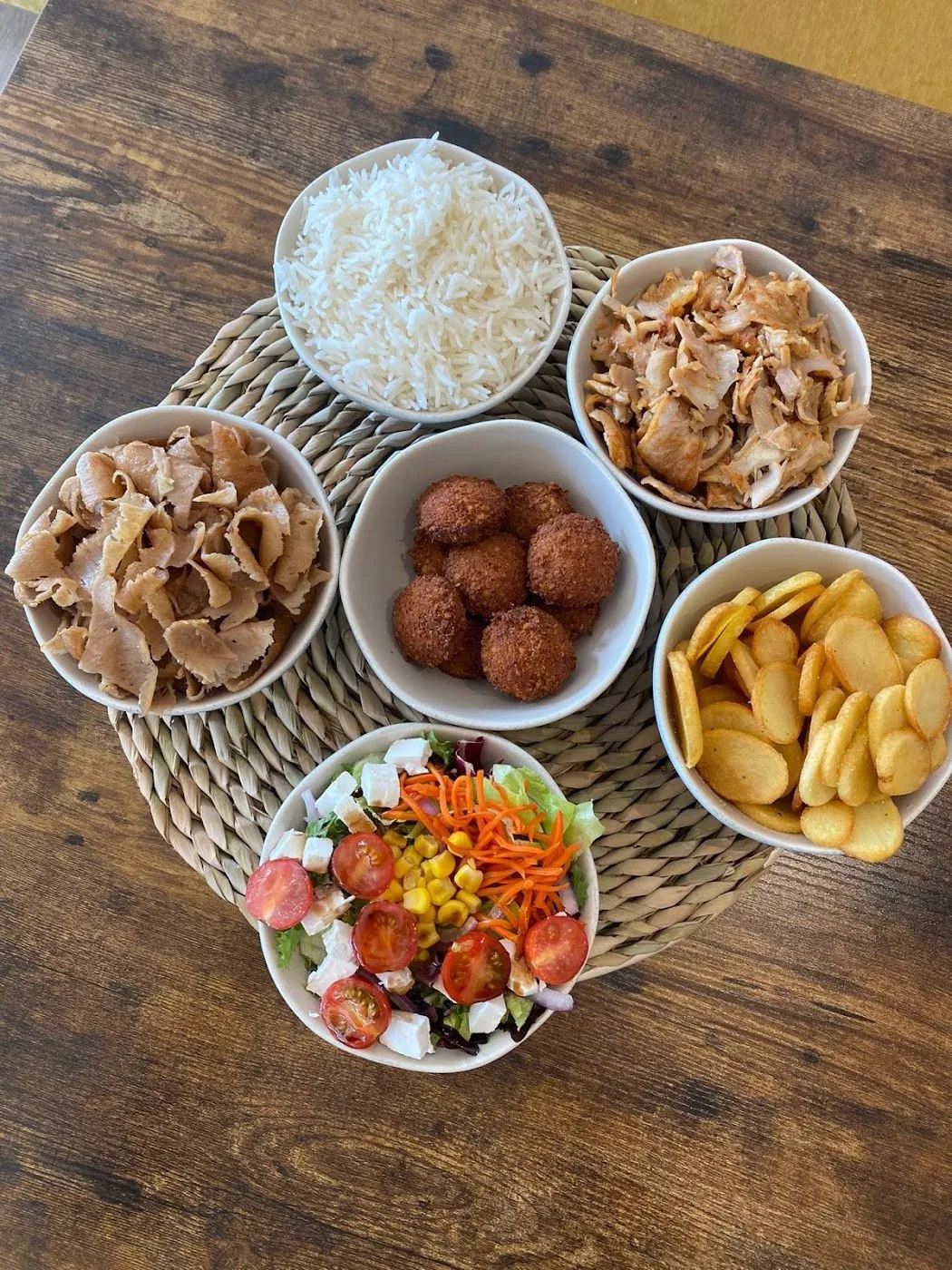 Cuencos de arroz, carne de kebab, falafel, patatas y ensalada